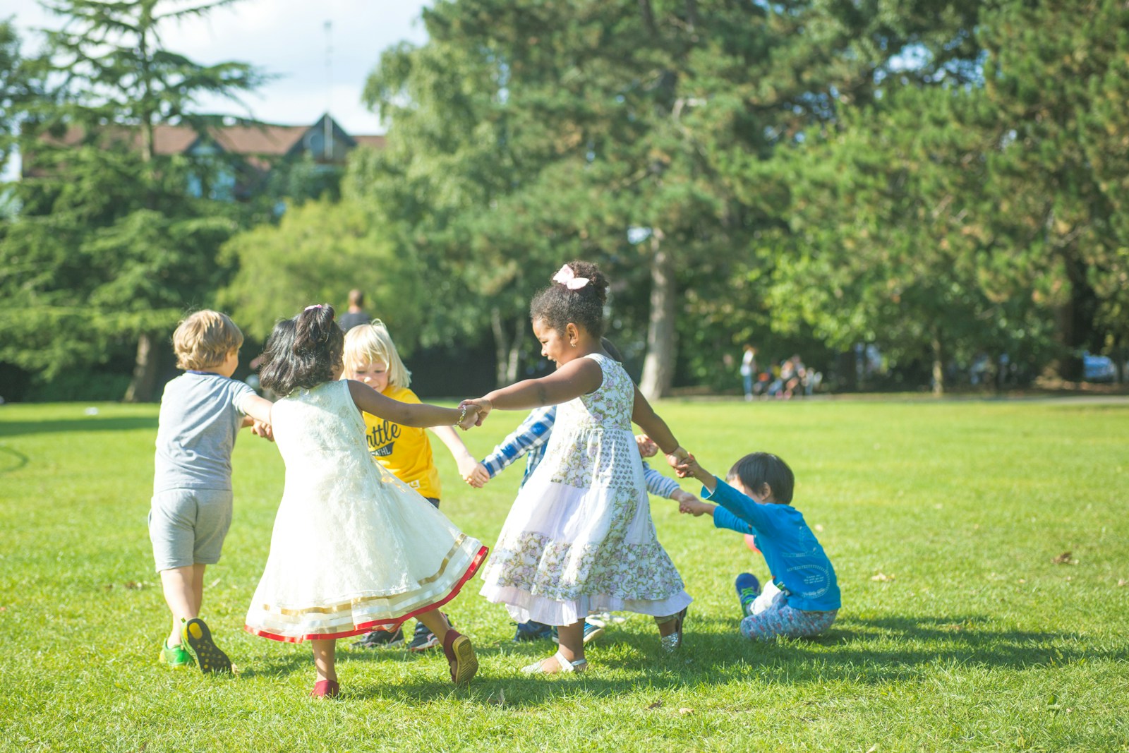 woman in white dress dancing with girl in white dress on green grass field during daytime